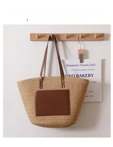Detail of woven straw tote bag featuring a leather pocket and dual-tone shoulder straps