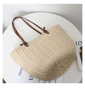 Detailed close-up of straw tote bag showing woven fiber texture and brown leather straps