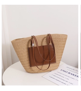 Detail of hand-woven straw tote bag with brown faux leather pocket on white surface