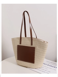 Detail of woven straw tote bag featuring brown leather handles and fine texture