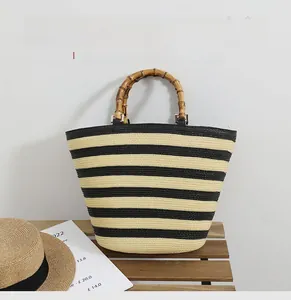 Detail of hand-woven straw tote with natural bamboo handles and striped pattern