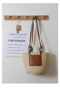 Detail of hand-woven straw bucket bag with leather pocket and slim brown strap