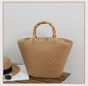 Detail of hand-woven straw tote with natural bamboo handles and summer holiday accessories