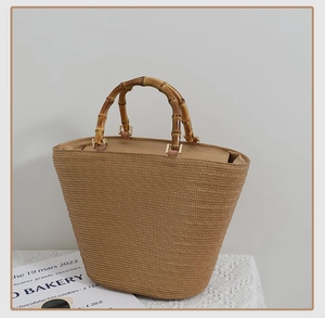 Detail of hand-woven straw tote bag featuring natural bamboo handles and metal buckle