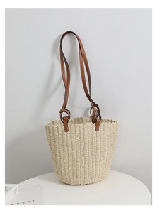 Close-up of handwoven straw bucket bag texture with adjustable brown leather shoulder strap