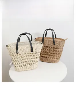Close-up of beige and brown hollow woven straw tote bags with black leather handles