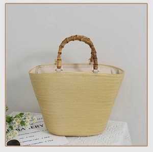 Detailed view of natural bamboo handles and woven texture on a French straw tote bag