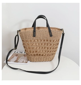 Detail of hollow woven straw tote with black leather handles and interior fabric lining