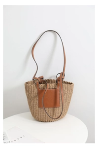Macro shot of hand-woven straw tote with premium brown leather handles and stitching