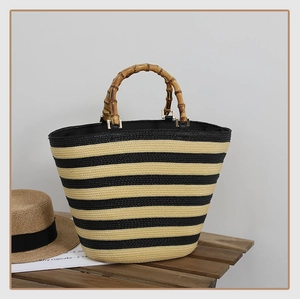 Detail of striped woven tote bag with bamboo handles and metallic gold hardware