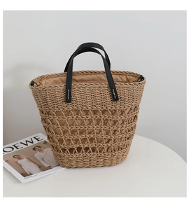 Close-up of vintage straw tote bag with hollow mesh design and black leather handles