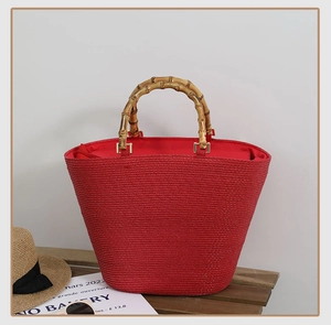 Detail of red woven straw tote bag featuring natural bamboo handles and summer holiday vibes
