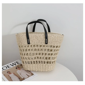 Detail of hollow woven straw tote with reinforced black leather handles for summer beach use