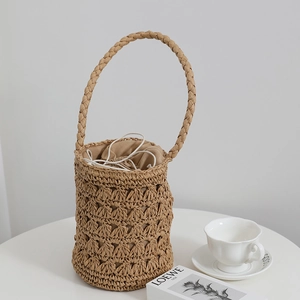 Sac seau en paille avec texture tressée et doublure à cordon sur une table blanche
