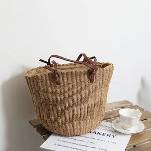 Retro hand-woven straw bucket bag with brown leather handles on a cafe table