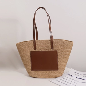 Large straw tote bag with brown leather straps and front pocket for beach vacation use