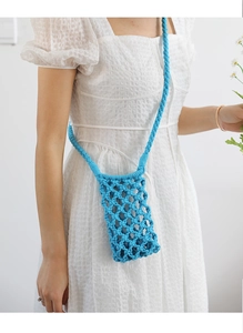 Detail of bright blue hand-woven crochet crossbody phone bag on a white dress