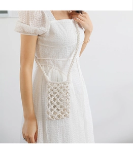 Detailed texture of white macrame woven phone bag worn by model on white dress