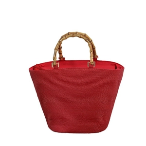 Red straw tote bag with natural bamboo handles and gold metal rings for summer
