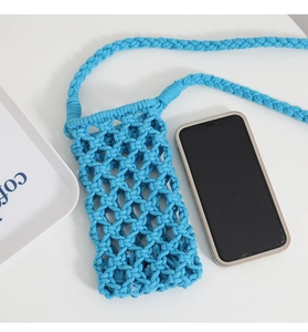 Macro shot of blue macrame cotton phone bag with braided strap on white desk