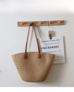 Close-up of straw tote bag showing detailed woven texture and brown leather handles