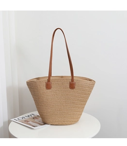 Detailed texture of hand-woven straw tote with premium brown leather shoulder straps