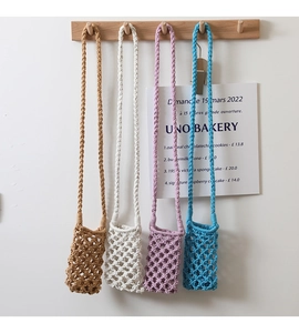 Detail showing four colorful crochet crossbody bags hanging on wooden hooks in a row