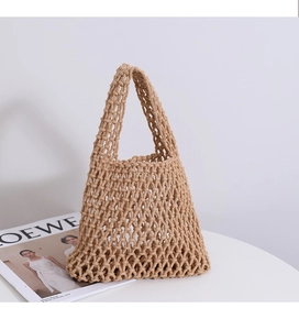 Close-up of khaki woven mesh tote bag with minimalist diamond knit pattern on white table
