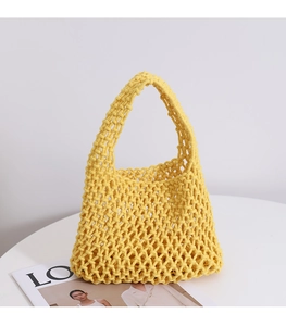 Detailed texture of the yellow cotton rope woven hollow handbag in a minimalist setting