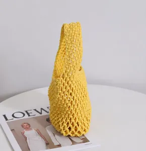 Macro-opname van de felgele macramé geweven draagtas op een witte ronde tafel