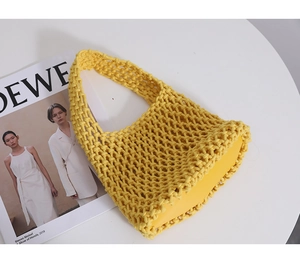 Detailed view of the bright yellow woven mesh bag with a reinforced solid base on a table