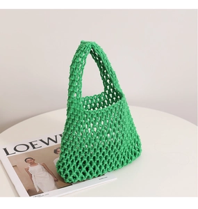 Detail of green handmade woven mesh tote bag with diamond pattern on white table