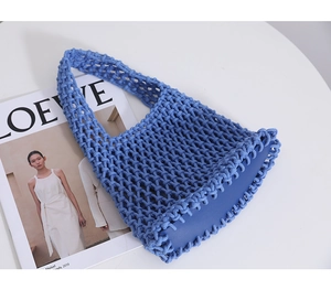 Detailed close-up of blue hand-woven cotton net bag with smooth synthetic leather base