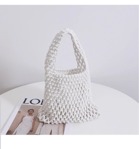 Close-up of white handcrafted woven rope tote bag with mesh knot pattern and sturdy handle