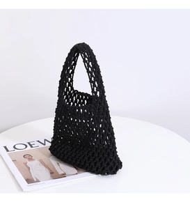 Detailed close-up of a black handmade woven mesh tote bag on a white minimalist background