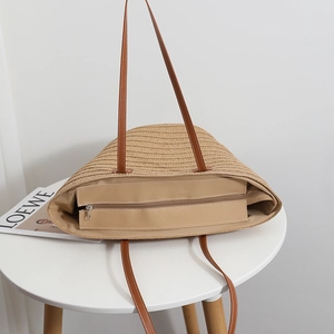 Large beige woven straw tote bag with brown leather handles for beach or casual travel
