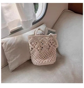 Close-up of bohemian ivory crochet bucket bag with hollow diamond patterns and floral details