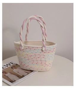 Close-up of cream woven cotton bag with colorful stitching and twisted pink handles