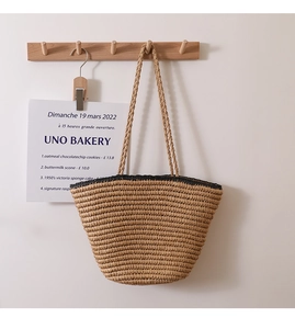Detail of hand-woven straw tote bag with black contrast trim for beach vacations