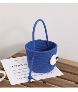 Macro detail of blue woven cotton bucket bag with cute cartoon eyes on a wooden table