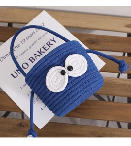 Macro detail of hand-woven blue cotton bucket bag with cute cartoon eye design and rope texture