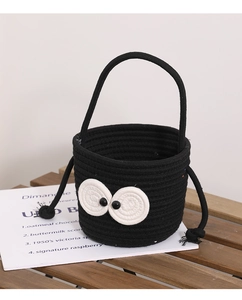 Close-up of black cotton woven bucket bag with large eyes and drawstring tassels