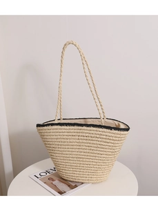 Detailed close-up of woven straw tote bag with black trim and fabric inner lining