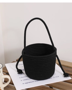 Detail of a black woven cotton rope bucket bag with large eye accents and top handle