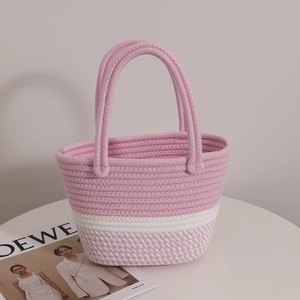 Pink and white woven cotton tote bag with braided handles on a white table