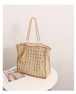 Dettaglio della trama traforata e nappa a frange sulla borsa da spiaggia in paglia beige