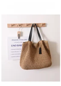 Close-up of woven straw bag with black leather handle and stylish tassel charm detail