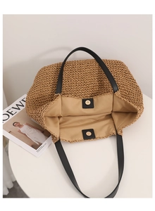 Detail view of khaki straw tote bag interior with magnetic snap and black leather handles