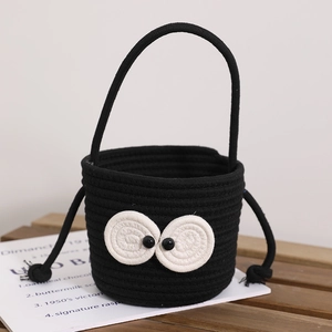 Handmade black woven bucket bag with large eye accents and a sturdy carrying handle