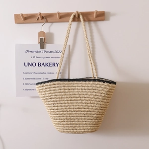 French vintage straw tote bag with black trim and long shoulder straps for beach vacations